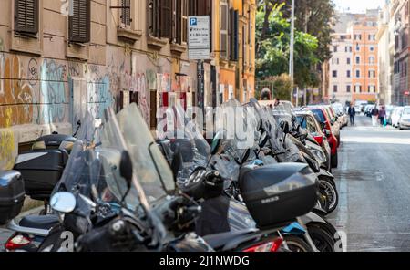 Ein Bild einer Straße in Rom mit einer langen Reihe von Motorroller auf der rechten Seite. Stockfoto