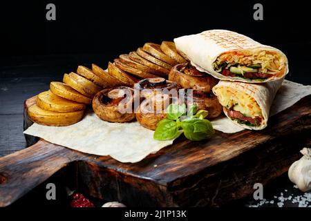 Traditionelle Shawarma, gebratene Kartoffeln und Pilze. Türkische Straßengerichte. Östliches Fast Food. Döner Kebab mit Garnierung Stockfoto