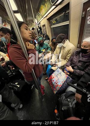 Die U-Bahn-Züge in New York City sind während der Hauptverkehrszeit wieder voll, wo es keine soziale Distanzierung mehr gibt. Im Frühjahr 2022 müssen die Fahrer immer noch Gesichtsmasken tragen. Stockfoto