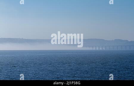 Dundee, Tayside, Schottland, Großbritannien. 27.. März 2022. Wetter in Großbritannien: Aufgrund der kalten Luft aus dem Westen bildet sich über den Fluss Tay dichter Nebel, der atemberaubende Ausblicke über Dundee bietet. Die Temperaturen fielen auf 14 Grad Später am Tag zerstreut die Sonne den Nebel, so dass der warme Sonnenschein scheint und die Temperaturen in Nordostschottland 18 Grad erreichen Spektakuläre Ausblicke von der Dundee-Uferpromenade auf die Tay Road Bridge, den Tay River, die Tay Railway Bridge und das V&A Design Museum im Frühjahr. Kredit: Dundee Photographics/Alamy Live Nachrichten Stockfoto