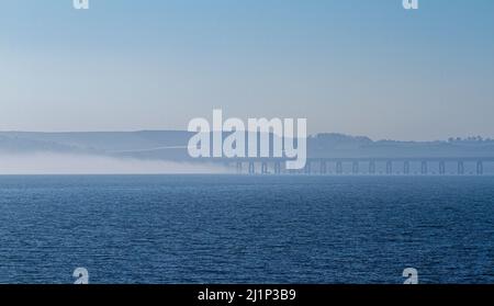 Dundee, Tayside, Schottland, Großbritannien. 27.. März 2022. Wetter in Großbritannien: Aufgrund der kalten Luft aus dem Westen bildet sich über den Fluss Tay dichter Nebel, der atemberaubende Ausblicke über Dundee bietet. Die Temperaturen fielen auf 14 Grad Später am Tag zerstreut die Sonne den Nebel, so dass der warme Sonnenschein scheint und die Temperaturen in Nordostschottland 18 Grad erreichen Spektakuläre Ausblicke von der Dundee-Uferpromenade auf die Tay Road Bridge, den Tay River, die Tay Railway Bridge und das V&A Design Museum im Frühjahr. Kredit: Dundee Photographics/Alamy Live Nachrichten Stockfoto