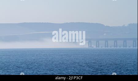 Dundee, Tayside, Schottland, Großbritannien. 27.. März 2022. Wetter in Großbritannien: Aufgrund der kalten Luft aus dem Westen bildet sich über den Fluss Tay dichter Nebel, der atemberaubende Ausblicke über Dundee bietet. Die Temperaturen fielen auf 14 Grad Später am Tag zerstreut die Sonne den Nebel, so dass der warme Sonnenschein scheint und die Temperaturen in Nordostschottland 18 Grad erreichen Spektakuläre Ausblicke von der Dundee-Uferpromenade auf die Tay Road Bridge, den Tay River, die Tay Railway Bridge und das V&A Design Museum im Frühjahr. Kredit: Dundee Photographics/Alamy Live Nachrichten Stockfoto