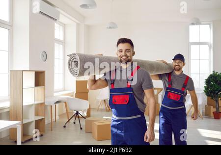 Lächelnde männliche Mover tragen Teppich auf den Schultern Stockfoto