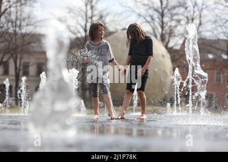 Aschersleben, Deutschland. 27. März 2022. Eine Wasserfontäne sorgt für Erfrischung in einem Stadtpark in Herrenbreite. Bei strahlendem Sonnenschein und warmen Temperaturen konnten viele Besucher den Frühling genießen. Quelle: Matthias Bein/dpa-Zentralbild/ZB/dpa/Alamy Live News Stockfoto