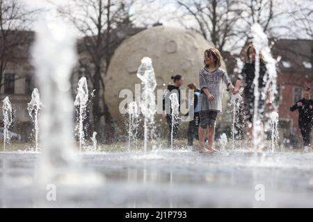Aschersleben, Deutschland. 27. März 2022. Eine Wasserfontäne sorgt für Erfrischung in einem Stadtpark in Herrenbreite. Bei strahlendem Sonnenschein und warmen Temperaturen konnten viele Besucher den Frühling genießen. Quelle: Matthias Bein/dpa-Zentralbild/ZB/dpa/Alamy Live News Stockfoto