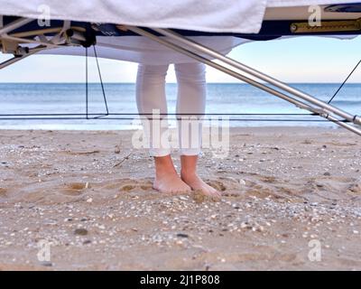 Blick auf die Füße eines jungen Chiromassage-Therapeuten und den Massageliege an einem Strand in Valencia, Spanien. Stockfoto