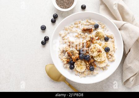 Haferflockenschale. Haferbrei mit Banane, Heidelbeere, Walnuss, Chiasamen und Mandelmilch für gesundes Frühstück oder Mittagessen. Gesunde Ernährung, Ernährung. Draufsicht. Stockfoto