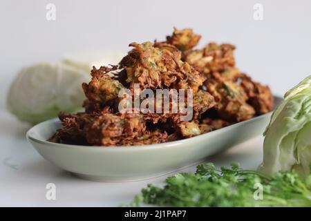 Indische Kohl-Krapfen. Hergestellt aus geschreddertem Kohl, Kichererbsenmehl, grünen Chilischoten, Korianderblättern und Gewürzen. Frittiert in Pflanzenöl. Häufig Stockfoto