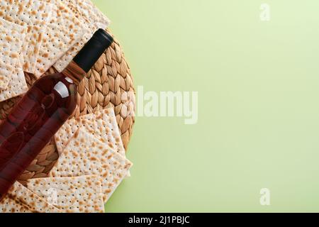 Konzept der Passahfeier. Matzah, roter Koscher und Walnuss. Traditionelles rituelles jüdisches Brot auf hellgrünem monochromen Hintergrund. Feder. Passah Stockfoto