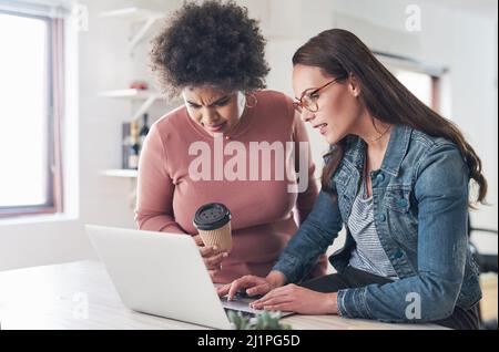 Wenn Sie etwas fachmännisch gestaltet haben möchten, rufen Sie es an. Aufnahme von zwei jungen Geschäftsfrauen, die in einem modernen Büro einen Laptop benutzen. Stockfoto