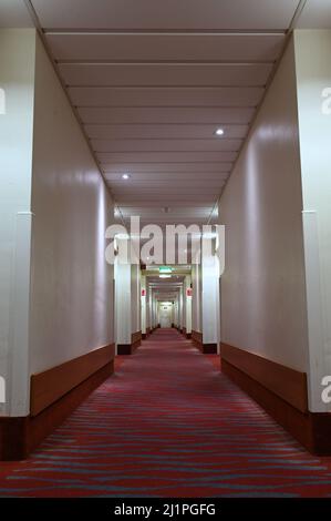 Langer Hotelkorridor mit rotem Teppichboden Stockfoto