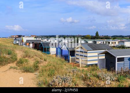 Hölzerne Strandhütten an der Küste hinter Sanddünen am Heacham North Beach, einem Küstendorf im Westen Norfolks, England, mit Blick auf die Wash Stockfoto