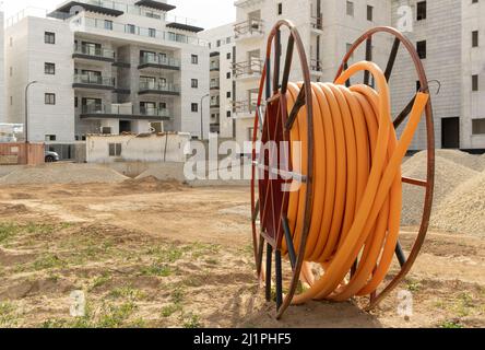 Schutz der Kabel in elektrischen Anlagen, Kommunikationsentwicklung, große Spulen aus orangefarbenem PVC-Rohrrohr, Kunststoff-pvc-Schläuche auf der Konstruktion Stockfoto