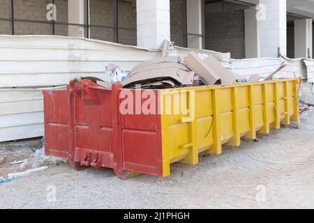 Ein riesiger Haufen Abfall in einem großen überlasteten Müllcontainer, der mit Bauabfällen gefüllt ist, Trümmer in der Nähe einer Baustelle. Stockfoto