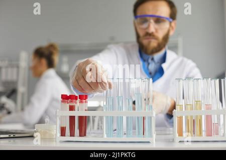 Nahaufnahme von Reagenzgläsern mit Blutproben und anderen chemischen Flüssigkeiten auf dem Tisch im Labor. Stockfoto