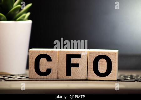 CFO Chief Financial Officer auf einem Holzwürfel vor einem Laptop geschrieben. Stockfoto