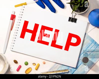 Das Wort Hilfe, auf einem Pflaster geschrieben ein Stück medizinisches Material, das verwendet wird, um eine Wunde zu bedecken. Weiße blanke Baumwolle isoliert auf einer schwarzen Oberfläche. Stockfoto