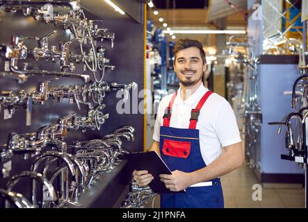 Fröhlicher Verkaufsassistent im Gang mit Wasserhähnen in einem Baumarkt oder Einkaufszentrum Stockfoto
