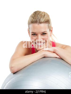 Lieben Sie sich ein wenig mehr. Studioaufnahme einer jungen Frau, die sich auf ihren Übungsball lehnt. Stockfoto