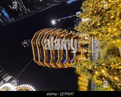 Eine vertikale Aufnahme des Schiffbaus in den Hudson Yards bei Nacht, mit Weihnachtsbäumen mit Lichtern auf der Straße Stockfoto