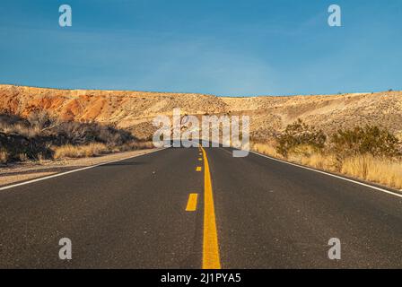 Overton, Nevada, USA - 11. Dezember 2010: Valley of Fire. Erdgeschossschuss über schwarzer Asphaltstraße mit gelber Trennlinie schneidet durch braune Wüste Stockfoto