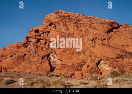 Overton, Nevada, USA - 11. Dezember 2010: Valley of Fire. Nahaufnahme eines roten Monstermundes mit Augen und Zähnen unter blauem Himmel. Vorne beige Wüste Stockfoto