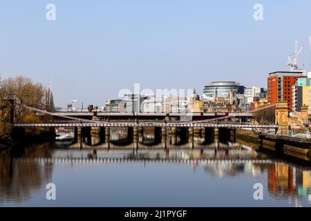 Blick nach Westen entlang des Flusses Clyde zur Hängebrücke der South Portland Street mit der Victoria Bridge dahinter und dem Broomielaw-Gehweg Stockfoto