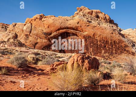 Overton, Nevada, USA - 11. Dezember 2010: Valley of Fire. Lanscape mit natürlichem Bogen auf roten Felsen der Bergkette unter blauem Himmel. Wüstenboden Stockfoto