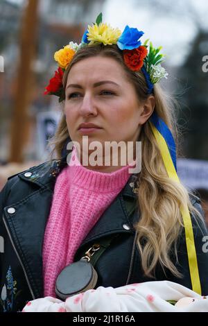 Madrid, Spanien. 27. März 2022. Während einer Kundgebung gegen die russische Invasion in der Ukraine wird ein Protestler gesehen, der eine Blumenkrone mit einem Band in Blau und Gelb trägt. Tausende von pro-ukrainischen Demonstranten demonstrieren gegen die russische Invasion, während sie sich von der Plaza de Espana (spanischer Platz) zur Plaza de Callao in Madrid, Spanien, versammeln. Kredit: SOPA Images Limited/Alamy Live Nachrichten Stockfoto
