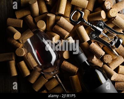 Festliche Komposition. Auf den Weinkorken liegt eine Flasche Rotwein, ein Korkenzieher und ein Weinglas. Auf dem Foto befinden sich keine Personen. Low-Angle-Ansicht. Weinprobe Stockfoto