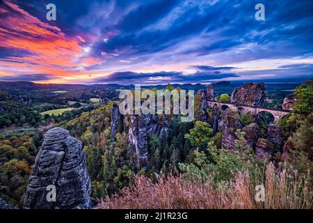 Landschaft mit den Felsformationen Felsenburg Neurathen und Bastei im Rathen-Gebiet des Nationalparks Sächsische Schweiz bei Sonnenaufgang. Stockfoto