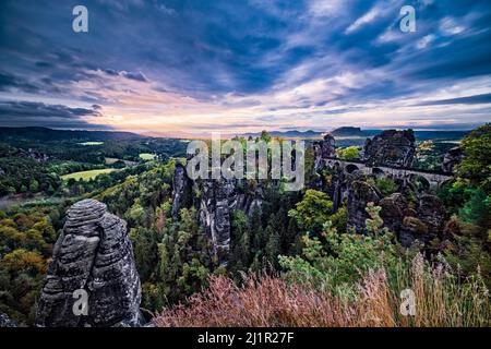 Landschaft mit den Felsformationen Felsenburg Neurathen und Bastei im Rathen-Gebiet des Nationalparks Sächsische Schweiz bei Sonnenaufgang. Stockfoto