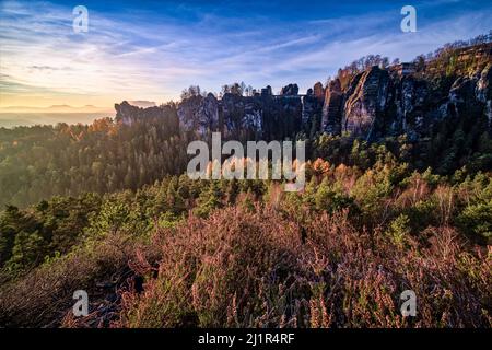 Landschaft mit den Felsformationen Felsenburg Neurathen und Bastei im Rathen-Gebiet des Nationalparks Sächsische Schweiz bei Sonnenaufgang im Herbst. Stockfoto