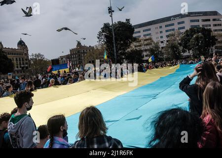 Barcelona, Spanien. 27. März 2022. Demonstranten halten eine große ukrainische Flagge während der Demonstration gegen die russische Invasion der Ukraine auf der Plaza de Catalunya. Kredit: SOPA Images Limited/Alamy Live Nachrichten Stockfoto