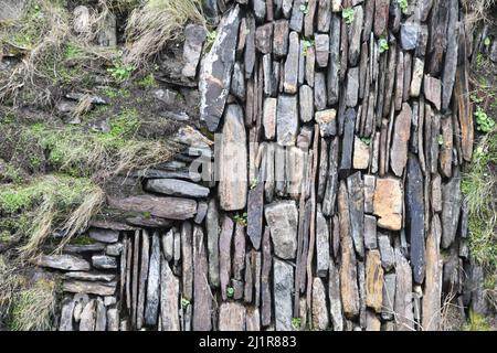 Steinmauer, die den Weg in Boscastle, Cornwall, Erde gefüllt mit Steinen und Felsen in vertikalen und horizontalen Strecken. Mit Gras bedeckt, pennywo Stockfoto