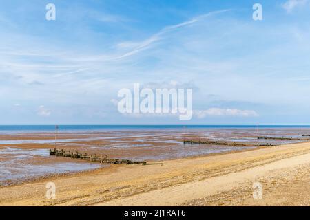 Hölzerne Groynes an einem einsamen Strand bei Ebbe am Ufer in Heacham, West Norfolk, England, mit Blick auf die Wash Stockfoto