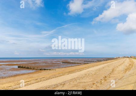Hölzerne Groynes an einem einsamen Strand bei Ebbe am Ufer in Heacham, West Norfolk, England, mit Blick auf die Wash Stockfoto