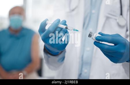 Die erste Impfserie wird ausgerollt. Zugeschnittenes Bild eines nicht erkennbaren männlichen Arztes, der die covid 19-Impfung für einen Patienten vorbereitet. Stockfoto