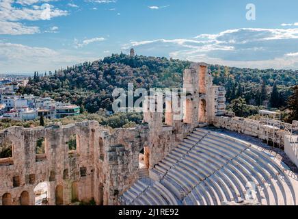 Das Odeon des Herodes Atticus, das sich am Südwesthang der Akropolis befindet, und der Filopappos-Hügel mit dem Filopappos-Denkmal auf der Spitze. Athen, Att Stockfoto