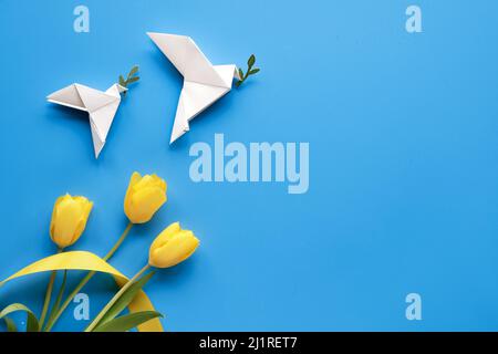 Taube des Friedens, Papier Origami. Frieden für die Ukraine. Gelbe Tulpen, Blumen, auf blauem Hintergrund. Copy-Space, für Text platzieren. Draufsicht, flach liegend, Stockfoto