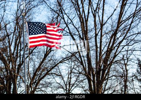 Schlecht zerrissene amerikanische Flagge, die von der Fahnenstange draußen fliegt Stockfoto