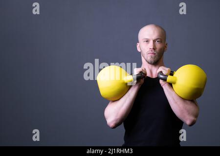 Typ mit einem gelben Kettlebell-Fitnessstudio, anonymer junger Mann, für einen fitgen Teenager, der sich für sportliche, vietnamesische Aktivitäten aus Gummi pflücken möchte. Gesunde Daunengesundheit Stockfoto