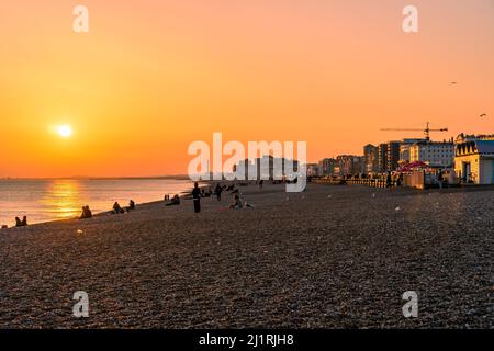 Hove, East Sussex, England. 27. März 2022. Der wunderschöne Sonnenuntergang am Sonntagabend entlang der Strandpromenade, während Hove an einem frühen Frühlingsabend am ersten Tag der britischen Sommerzeit in der untergehenden Sonne leuchtet.©Sarah Mott / Alamy Live News Stockfoto