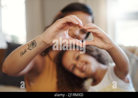 Wir haben viel Liebe zu teilen. Aufnahme einer unkenntlichen Frau, die sich zu Hause mit ihrer Tochter verbunden und eine herzförmige Geste macht. Stockfoto