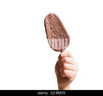 Die Hand eines Kindes hält ein Schokoladeneis auf einem Stock, einem Popsicle mit Nüssen, isoliert auf weißem Hintergrund. Stockfoto