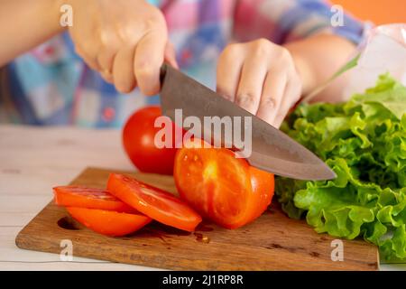 Rote Tomaten auf dem Schneidebrett, in der Küche. Der Prozess des Kochens, Nahaufnahme. Stockfoto