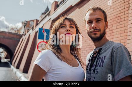Ein Porträt eines jungen, liebenden Paares, das sich vor einer Ziegelwand posiert Stockfoto