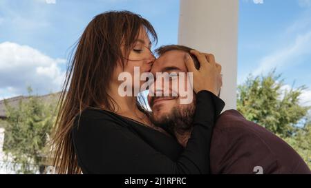 Eine junge schöne Frau mit langen dunklen Haaren küsst Stockfoto