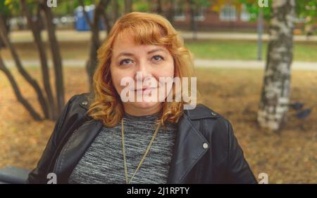 Das Porträt einer schönen lächelnden Frau läuft im Herbstpark Stockfoto