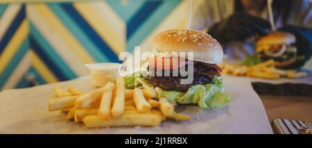 Saftiger Hamburger mit zwei Koteletts mit Pommes frites. Stockfoto